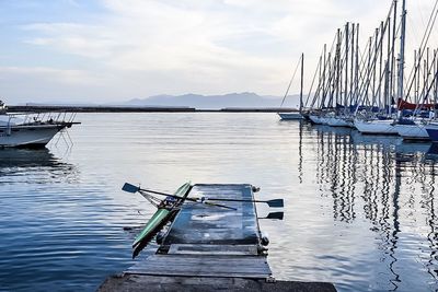 Kayak moored by jetty in sea at harbor against sky