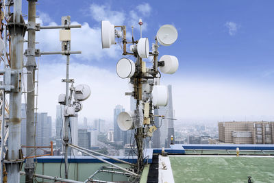 Communications tower in city against sky