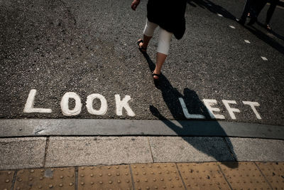 Low section of woman walking by road sign 