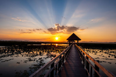 Pier over sea against sky during sunset