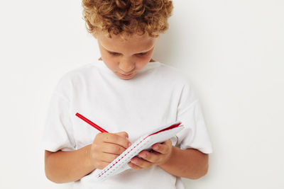 Midsection of woman writing in book against white background