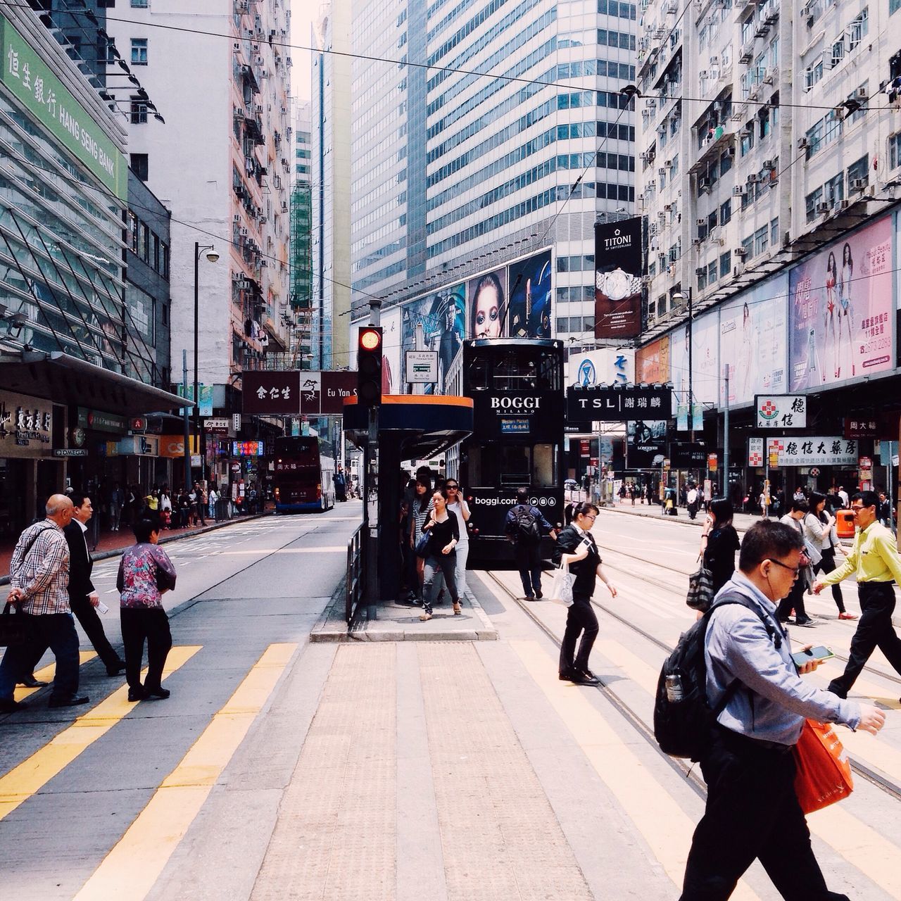 city, building exterior, large group of people, architecture, street, men, built structure, city life, person, walking, lifestyles, transportation, city street, road, leisure activity, road marking, zebra crossing, day, outdoors