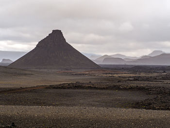 Scenic view of desert against cloudy sky