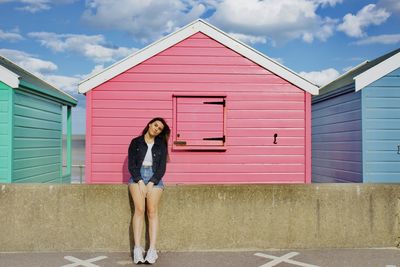 Portrait of woman standing against pink wall