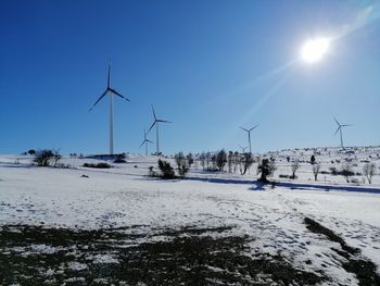 Wind turbines on land against sky during winter