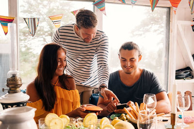 Young men and woman using mobile phone at dinning table