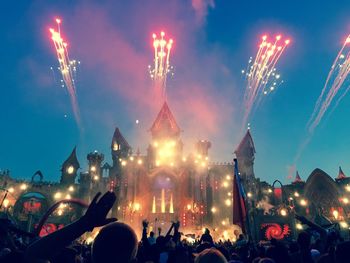 Fans against firework display against sky at tomorrowland