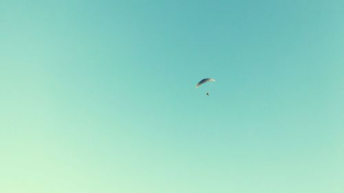 Low angle view of paragliding against clear blue sky