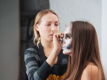 Beautician applying make-up to young woman