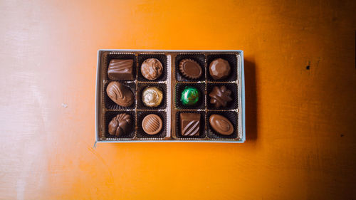 Directly above shot of chocolates in box on wooden table
