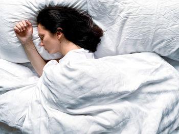 Side view of woman sleeping on bed