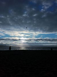 Silhouette man standing on beach against sky during sunset