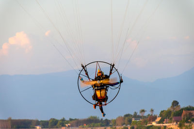 Close-up of person paragliding against sky