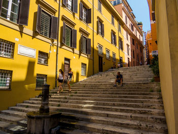 People walking on staircase amidst buildings in city