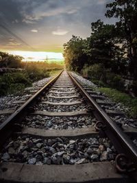 Railroad track on field against sky during sunset