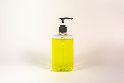 Close-up of yellow glass bottle on table against white background