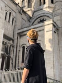 Rear view of woman standing against building in city