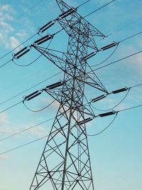 Low angle view of electricity pylon against blue sky