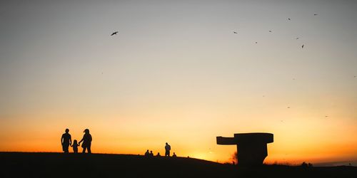 Silhouette people flying against sky during sunset