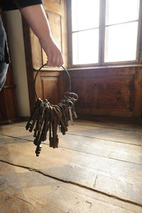 Low section of man holding shoes hanging on wooden floor