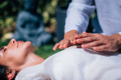 Woman in reiki spiritual healing session. reiki therapist holding hands above heart chakra 