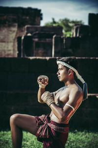 Full length of young woman holding drink sitting outdoors