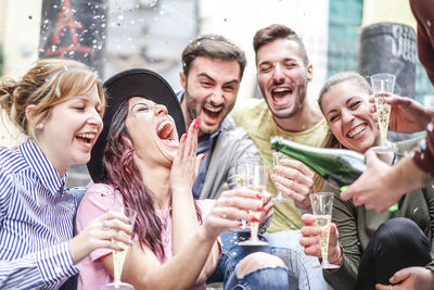 Cheerful male and female friends enjoying champagne during party outdoors