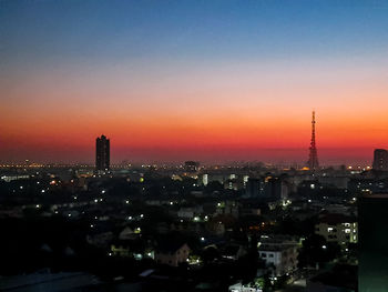 Illuminated modern buildings against romantic sky at sunset