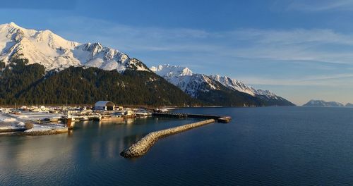 Scenic view of sea by snowcapped mountains against sky