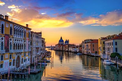 Boats moored in city at sunset