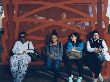 Portrait of smiling young women standing against people