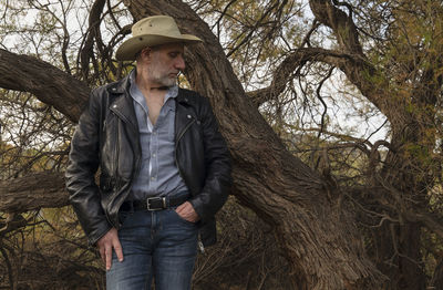 Portrait of adult man in cowboy hat against tree