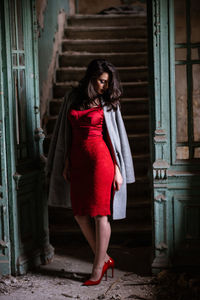 Portrait of woman standing against red door