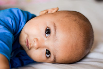 Close-up portrait of cute baby girl lying on bed