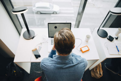 High angle rear view of businessman working at desk in office