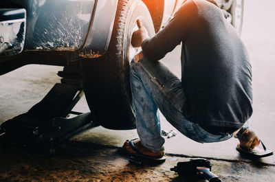 Low section of man working on motorcycle