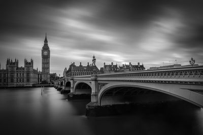 Arch bridge over river against sky in city