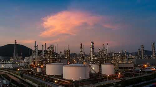 Illuminated factory against sky during sunset