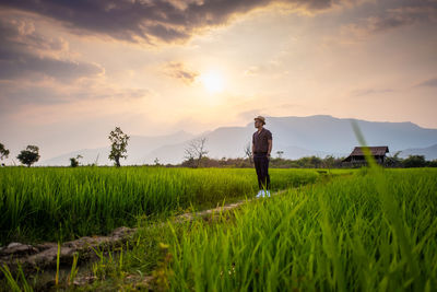 Man standing on field against sky during sunset