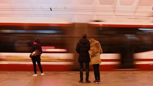 Rear view of people standing at railroad station