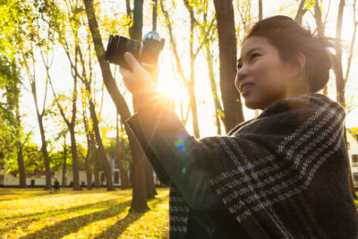 Portrait of young woman holding plant in sunlight