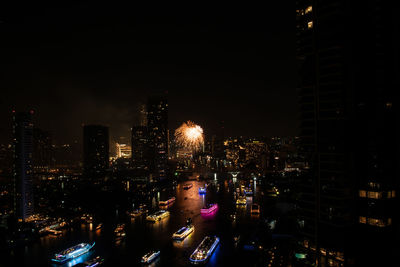 Illuminated street amidst buildings against sky at night