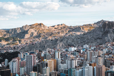 Aerial view of buildings in city against cloudy sky