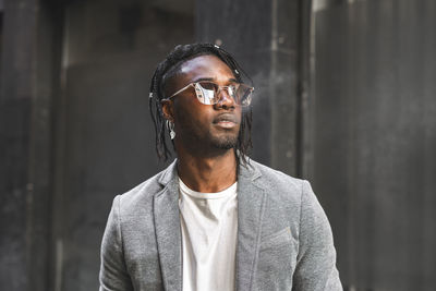 Fashionable young man smoking while looking away in city