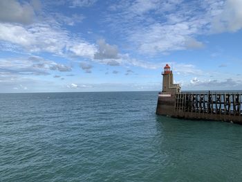 Lighthouse by sea against sky