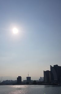 Silhouette buildings by sea against sky in city