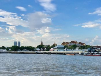 Buildings by sea against sky