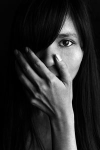 Close-up portrait of shocked young woman against black background