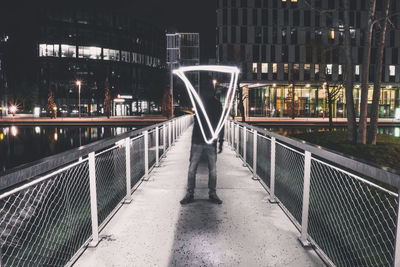 Rear view of man standing on footbridge in city