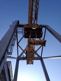 Low angle view of crane against clear blue sky